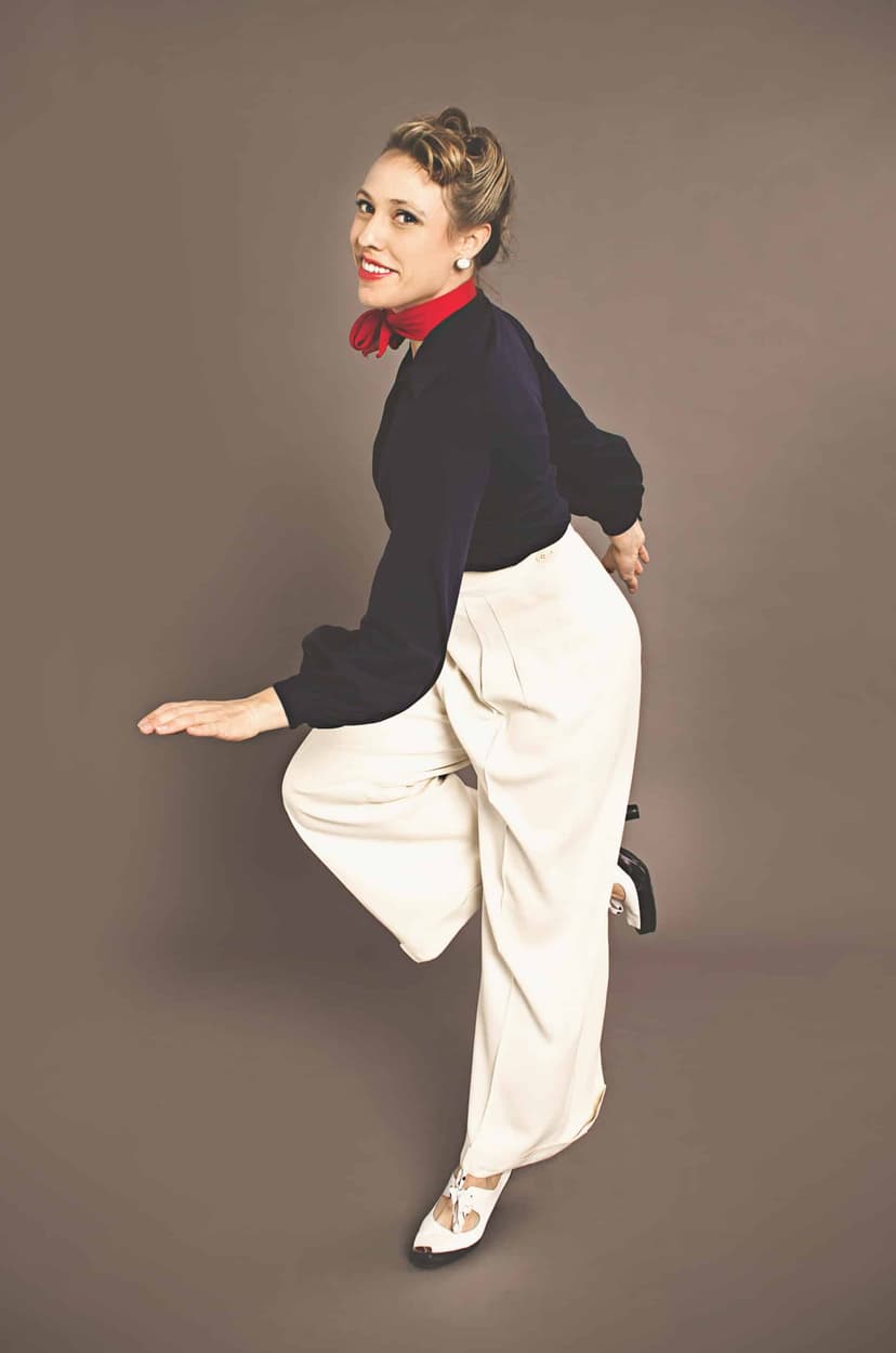 Laura Keat in white wide-leg trousers mid-step in a solo jazz pose