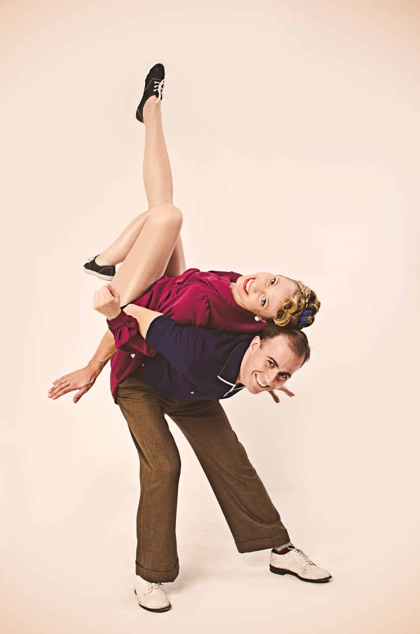 Two swing dancers in vintage clothes in a back-to-back lift