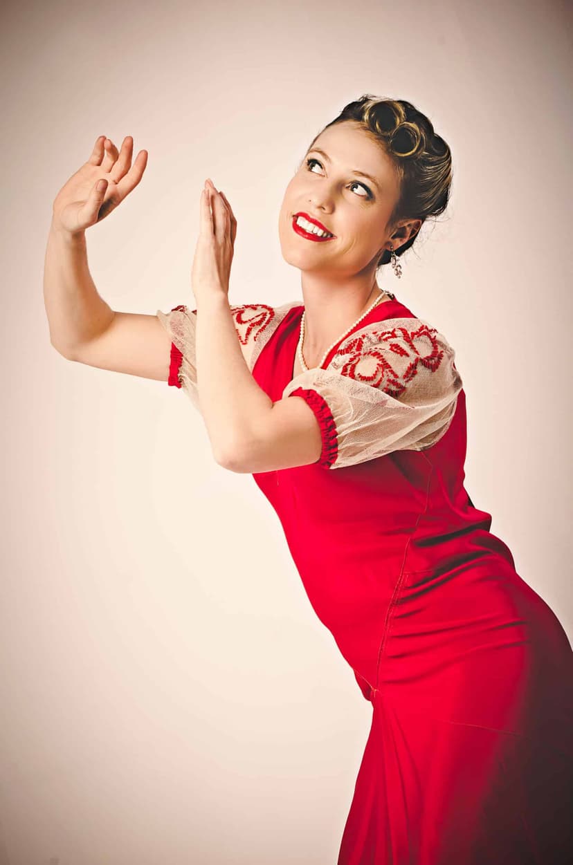 Laura Keat in a red dress striking a jazz pose