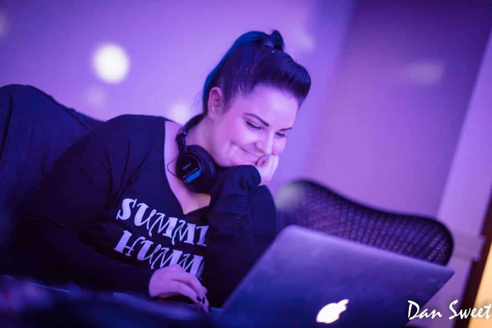 Kristen Shaw smiling at her laptop while editing, wearing headphones