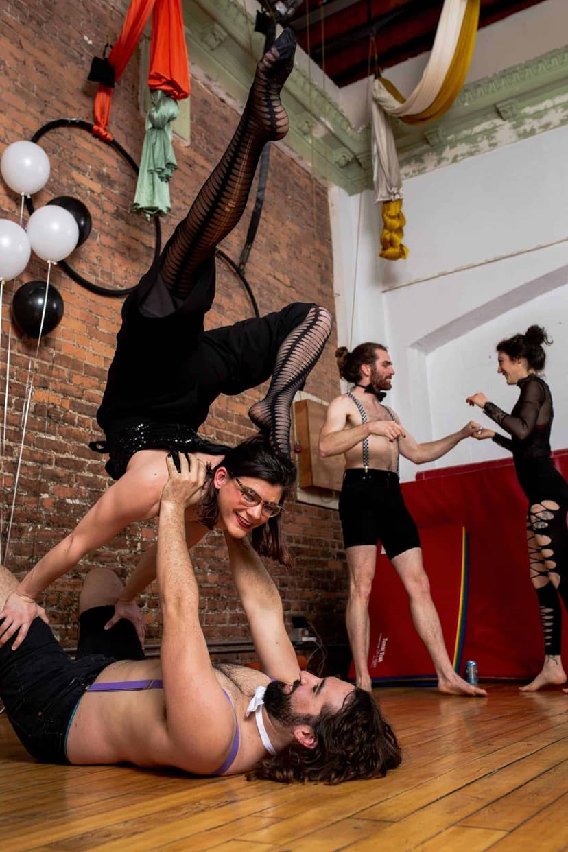 An acroyoga balance in a studio, one dancer upside down on a partner lying on the floor