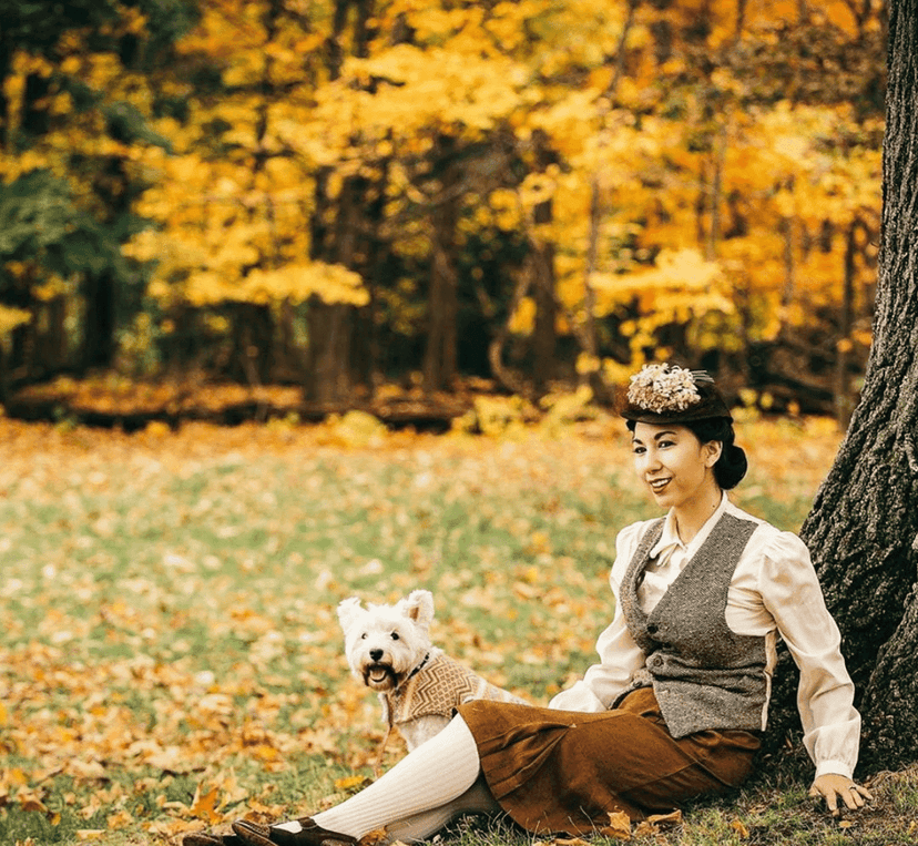 Instagram photo of Stina Dallons sitting under a tree in autumn leaves with a West Highland terrier