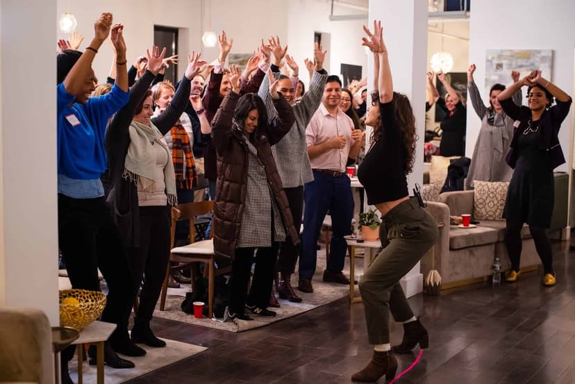 Jess Grippo leading a room full of people in a dance with their arms raised